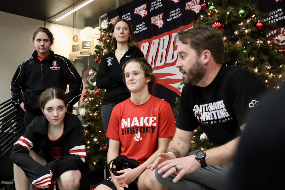 Coach Susan Fajardo, Coach Abby Lyman, Hazel Boerner ‘26, Sierra Pruessner ‘24, and Coach Ryan Ahlers gather with the rest of the team after City High‘s 9 point win over Western Dubuque
