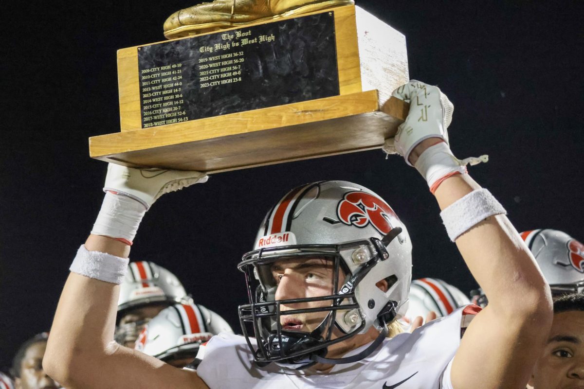 Drew Nye '25 holds the Boot Trophy over his head to celebrate the win over West High School.