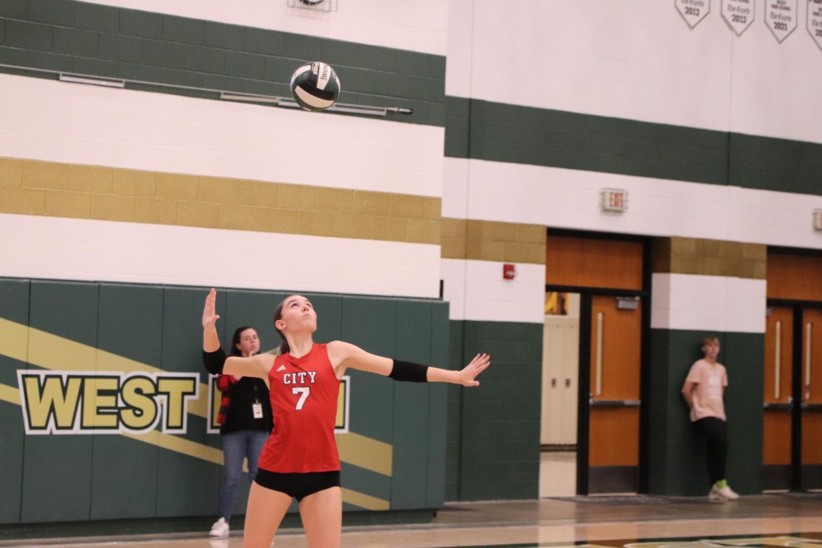 Lila Howe '25 attempts a serve vs rivals West High 