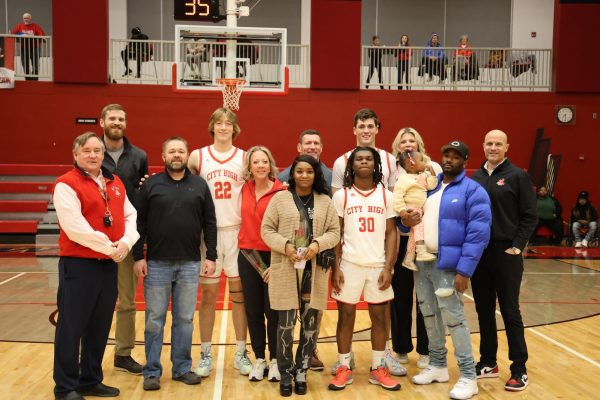 The seniors pose for a picture alongside their family and coaches.  From the left senior forward 22 Jaxton Schroeder, 30 guard Jay'den Williams, and in the back forward Parker Sutherland. 