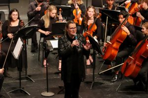 Orchestra Director, Megan Stucky-Swanson addresses the audience before the Philharmonic Orchestra performs their final piece.